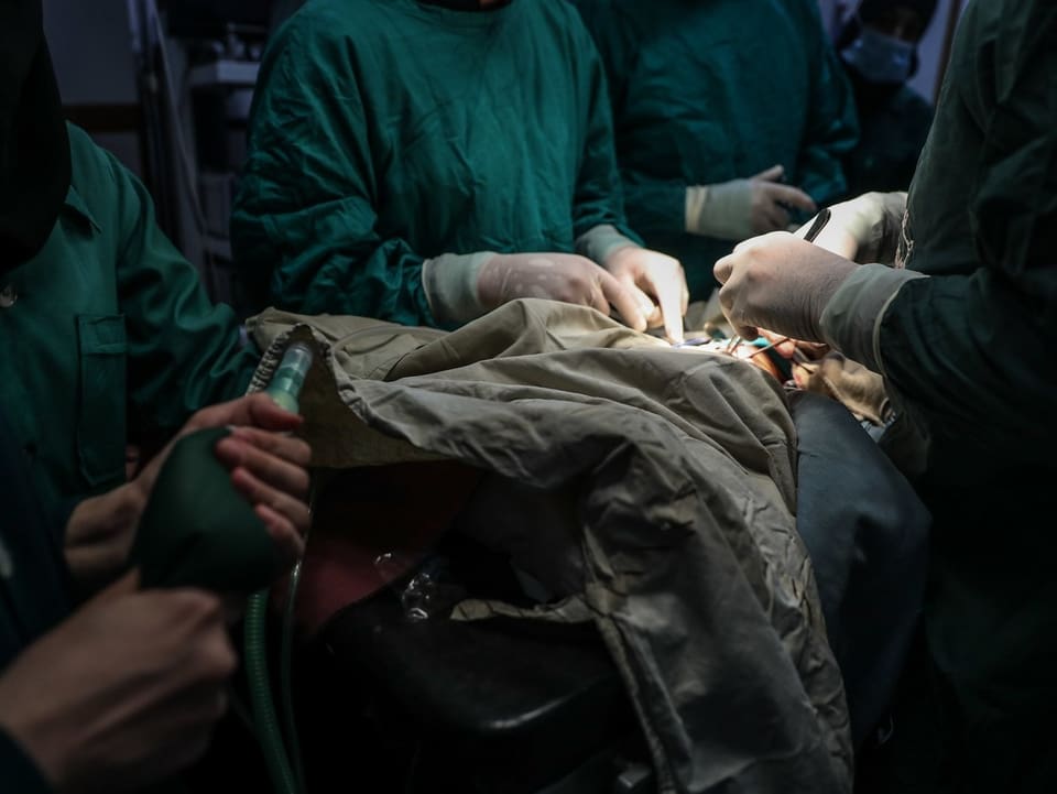 Schwach beleuchteter Operationssaal mit fünf Chirurginnen