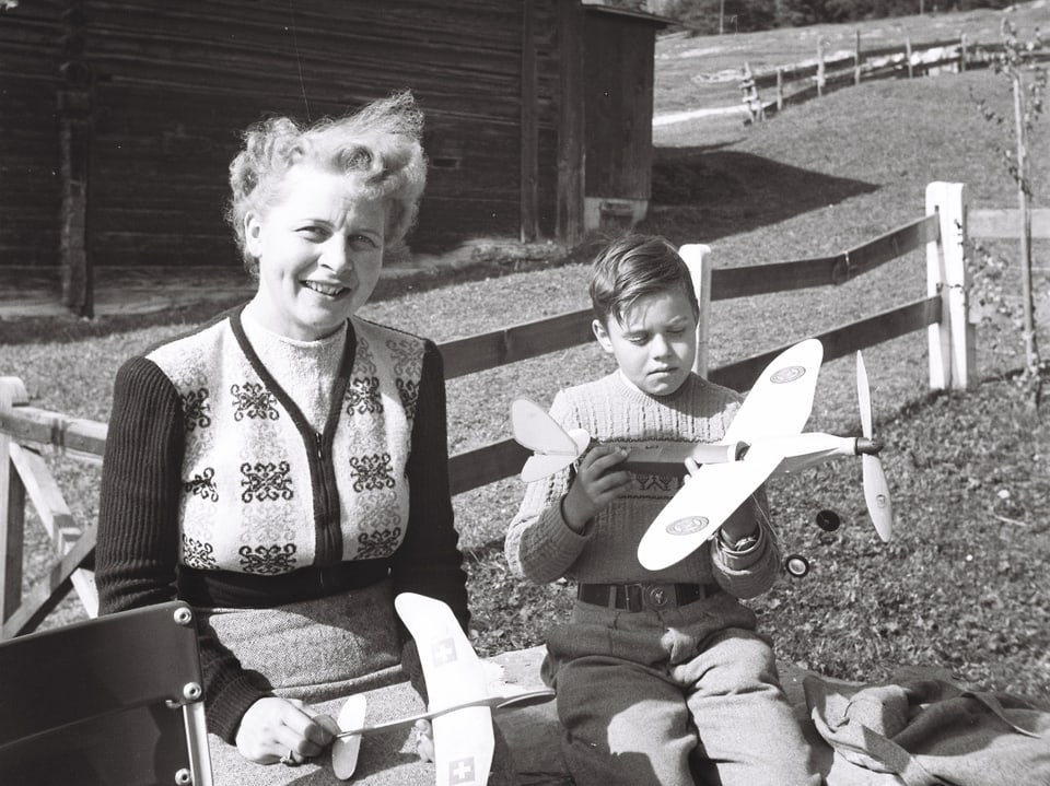 Lächelnde Frau und Junge mit Modellflugzeugen im Freien.