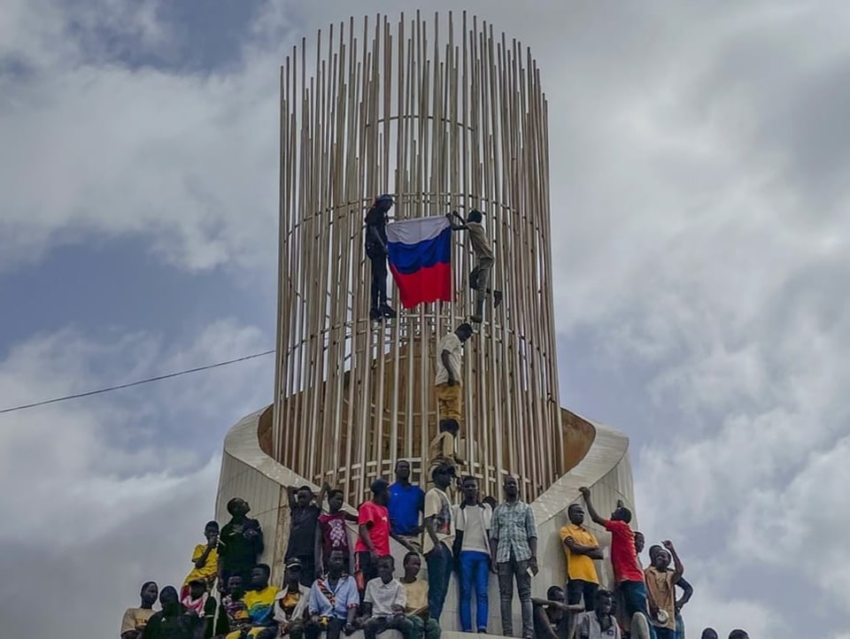 Menschen klettern auf einen Turm und hissen eine russische Flagge.