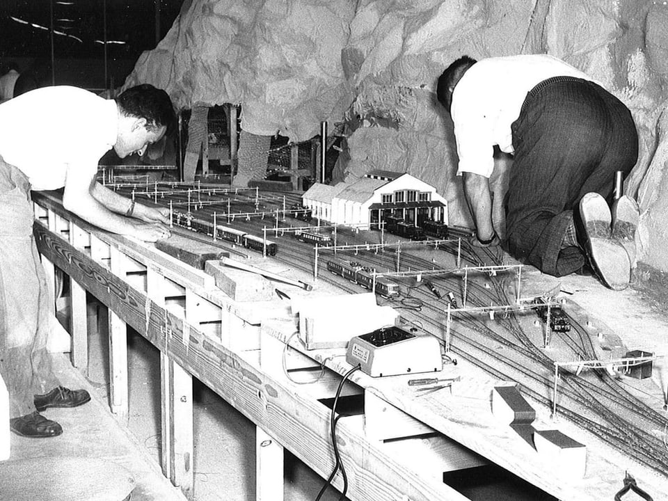 Männer arbeiten an Bahnmodell