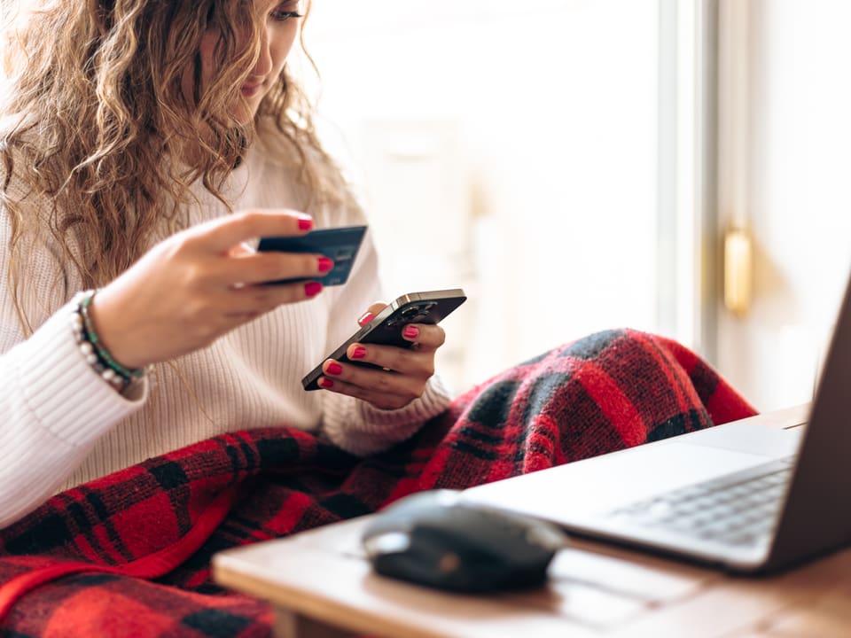 Frau mit Handy, Kreditkarte und Laptop