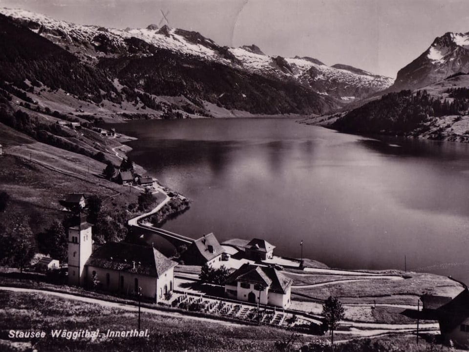 Stausee Wägithal in den Bergen mit Dorf im Vordergrund.