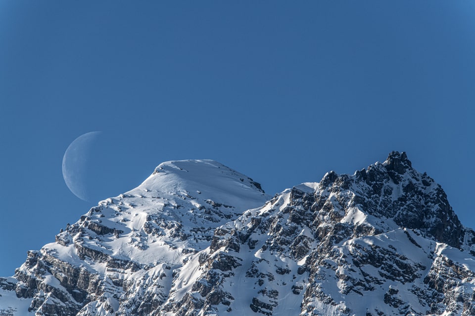 Der Mond gleitet sanft über den Piz Pisocs, während die Nacht hereinbricht.