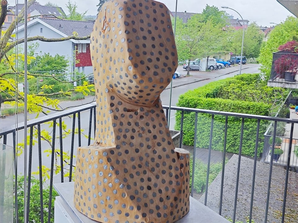 Skulptur auf einem Balkon mit Blick auf eine Wohngegend.