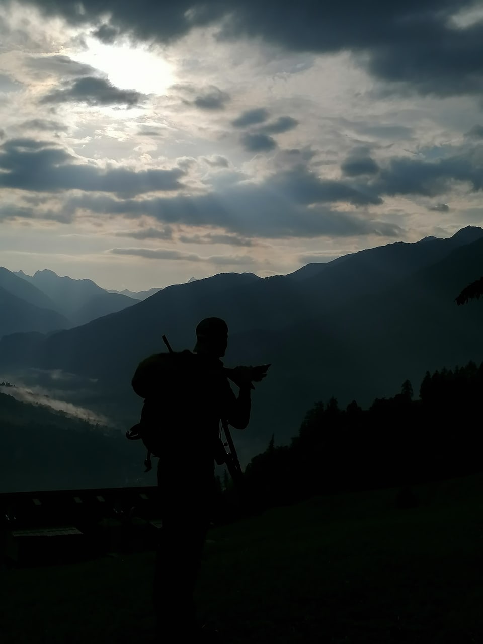 Silhouette eines Wanderers vor einer Berglandschaft bei Sonnenuntergang.