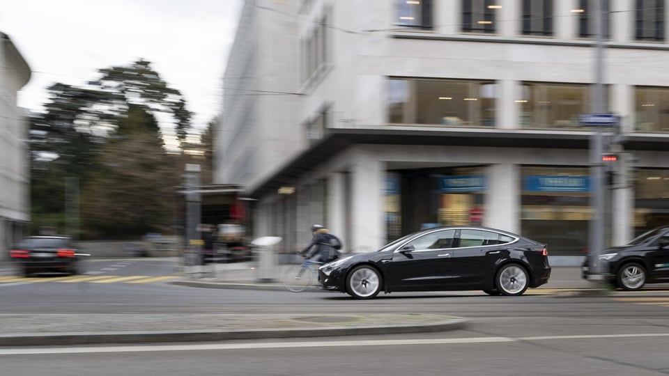 Tesla fährt durch eine Stadtstrasse.