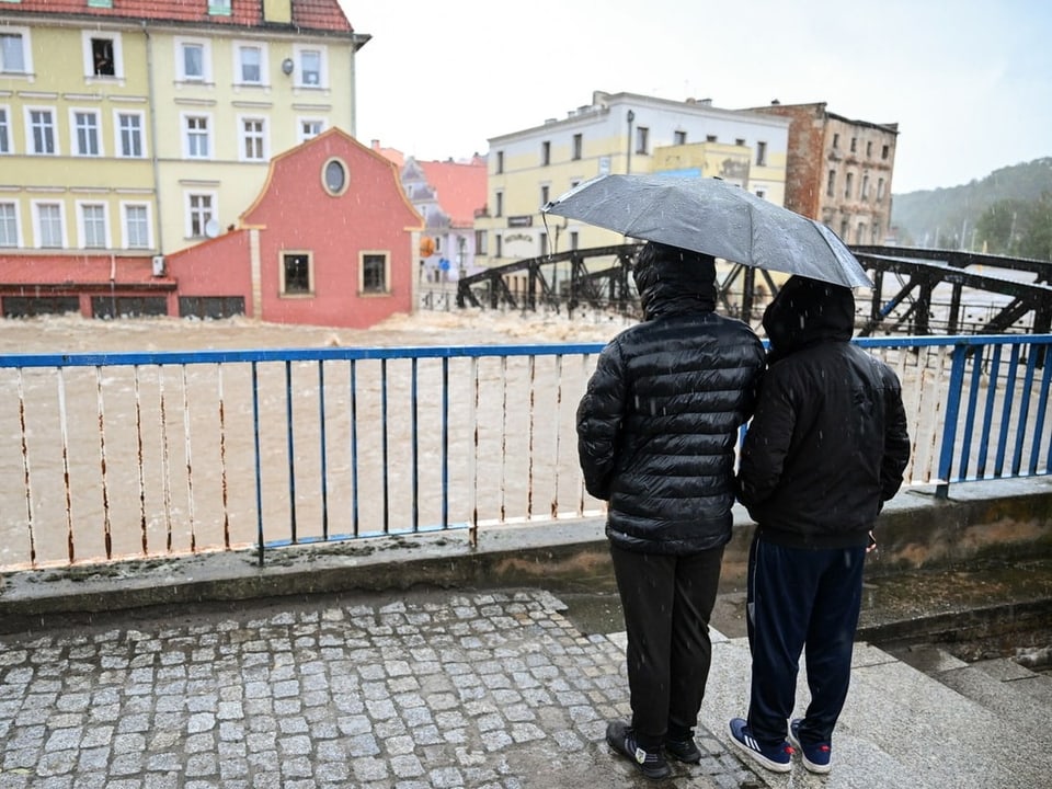 Zwei Menschen bestaunen die Wassermassen eines Flusses