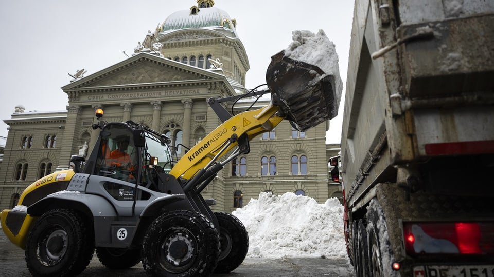 Radlader lädt Schnee vor dem Parlamentsgebäude.