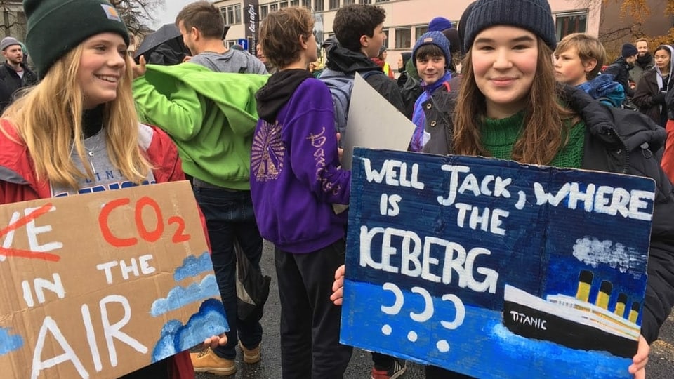 Zwei Mädchen halten Schilder mit Schriftzügen zum Klimaschutz in den Händen. 