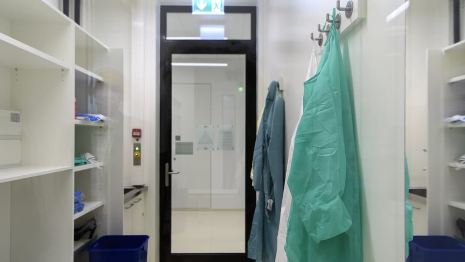 Kleiderhaken mit Arztschürzen im Eingang eines Forschungslabors.