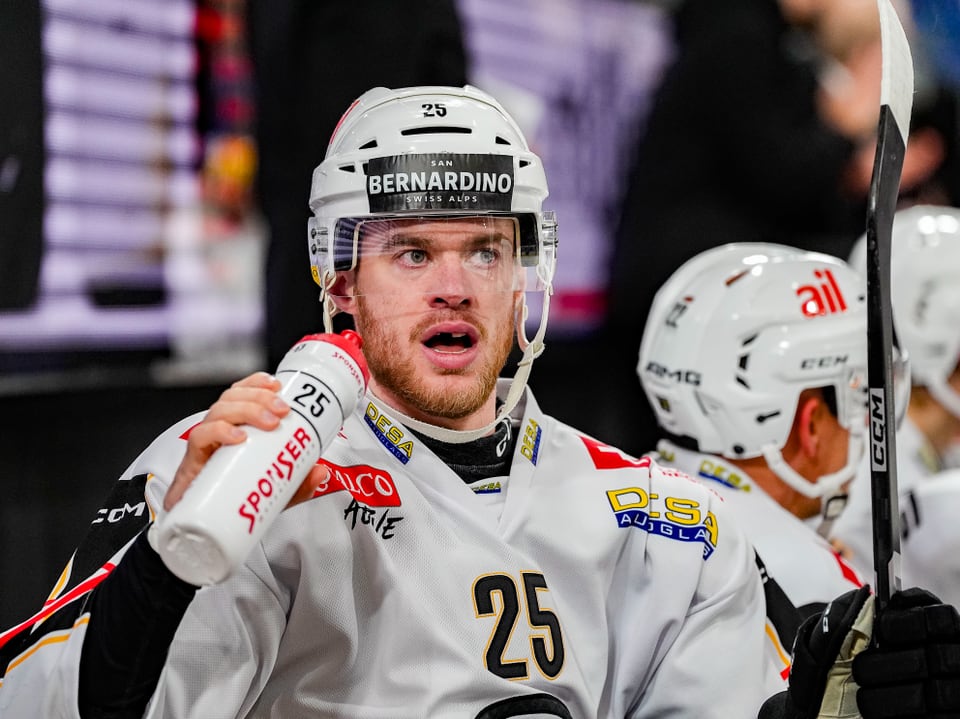 Eishockeyspieler auf der Bank hält Trinkflasche.