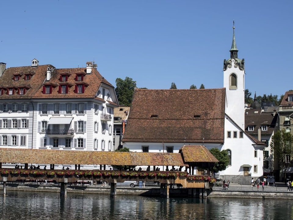 Im Vordergrund die Kapellbrücke in Luzern. Dahinter die Peterskapelle und ein anderes Gebäude.