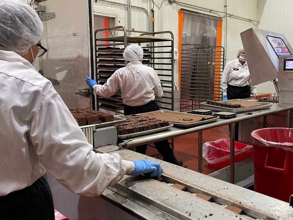 Mitarbeiter in einer Schokoladenfabrik an einer Produktionslinie.