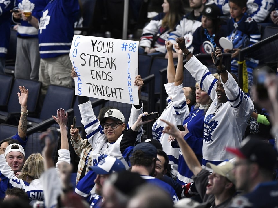 Eishockeyfans halten Schild mit motivierender Nachricht.